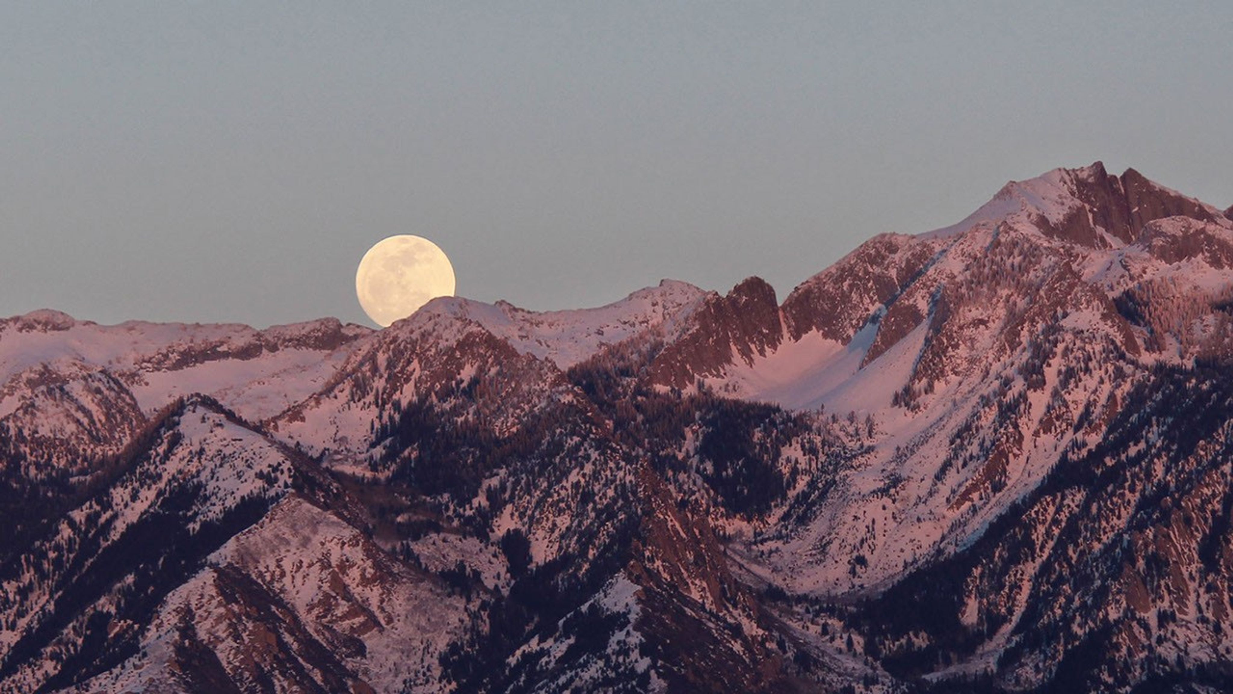 Moon rising over mountain peaks.