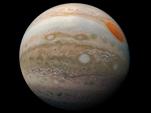 An orb is shown with a bright red oval at the upper right and with alternating bands of white, tan, and brown.