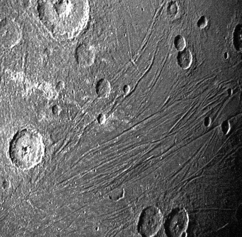 A pockmarked grey surface is shown. Long striations cut across the surface.