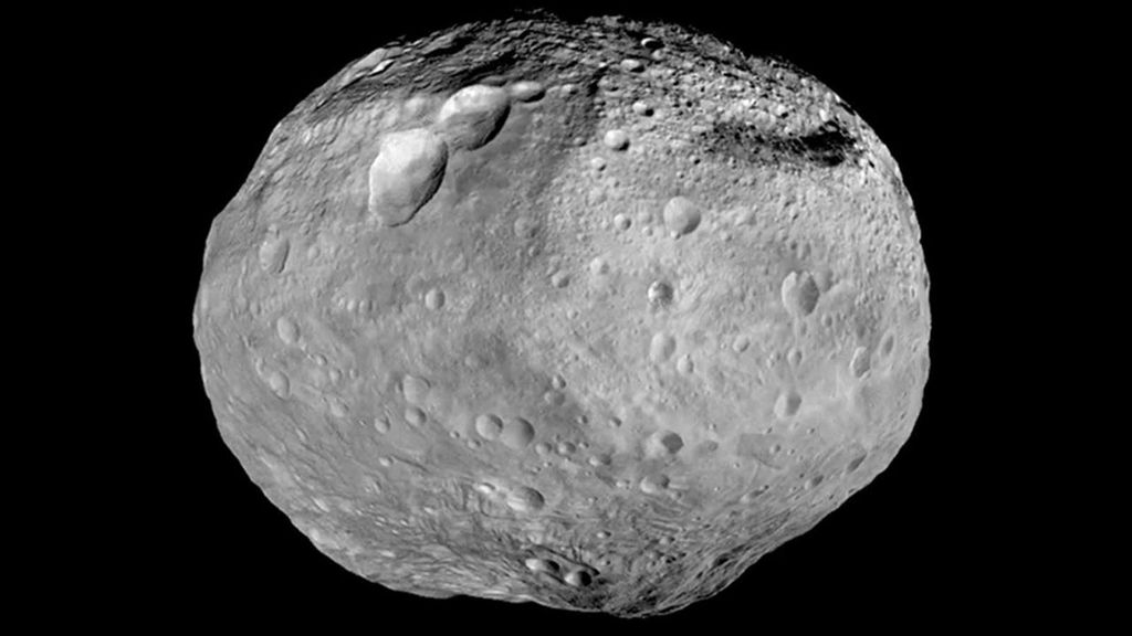 A mostly round asteroid Vesta with large craters visible.